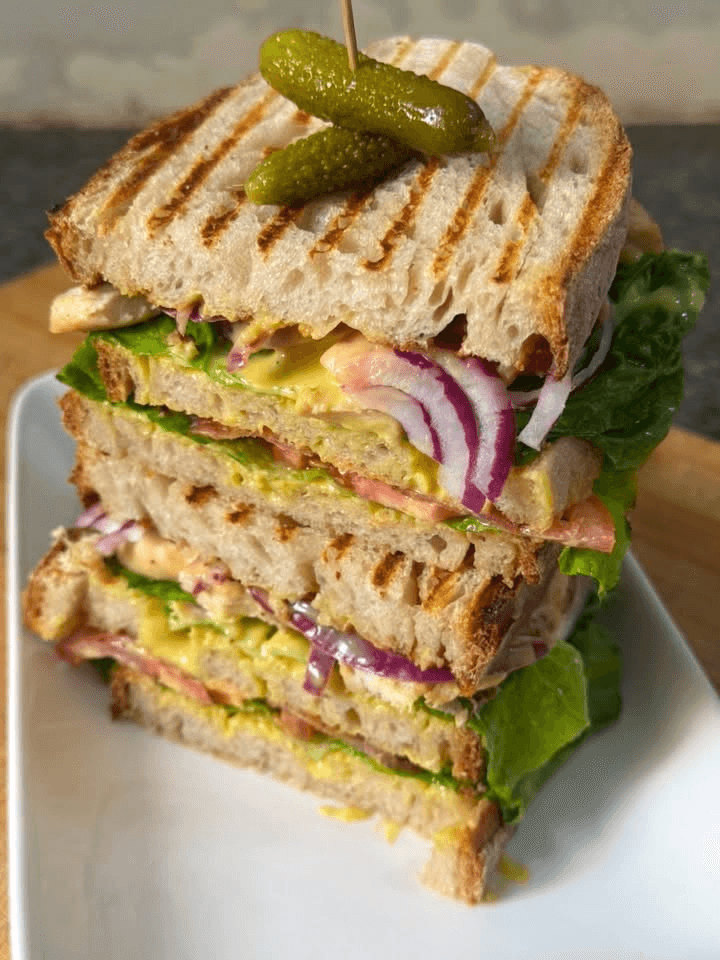 Grilled club sandwich with chicken, lettuce, tomato, and honey mustard